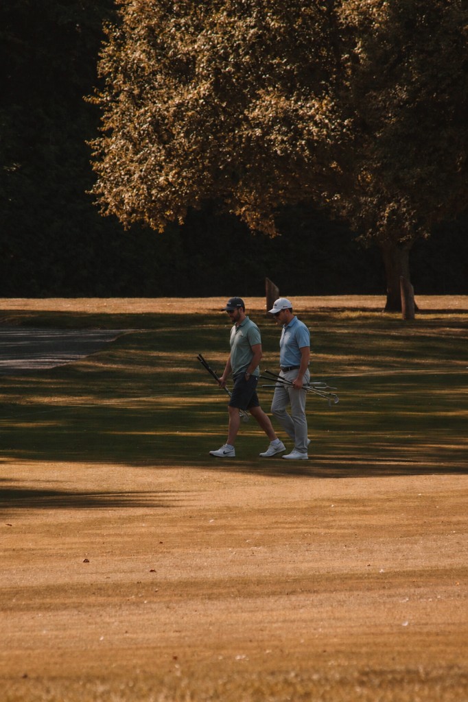 Two golfers walking together across a fairway